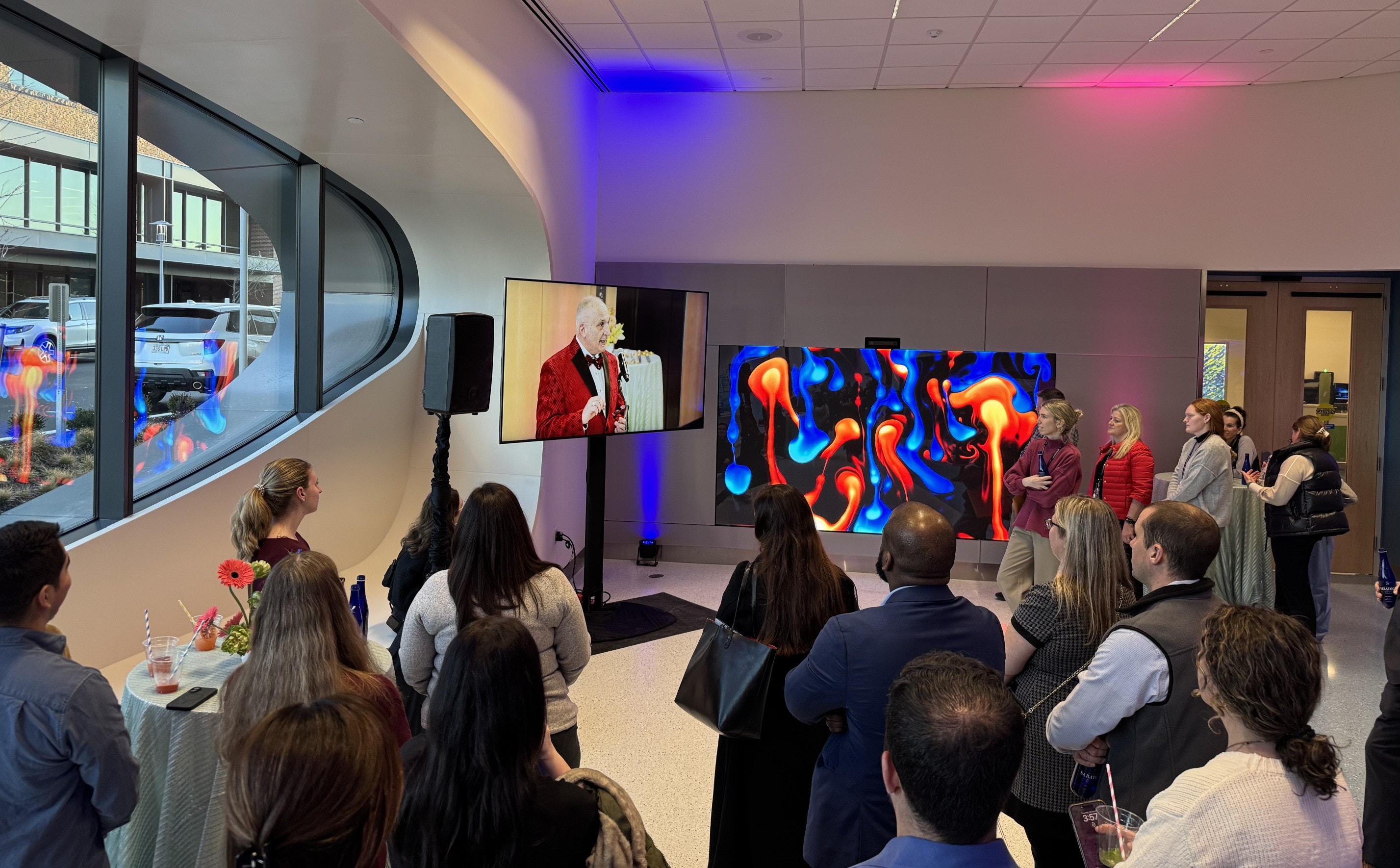 Boston Children's Hospital LED display during dedication event showing vibrant blue and orange generative art with attendees gathered